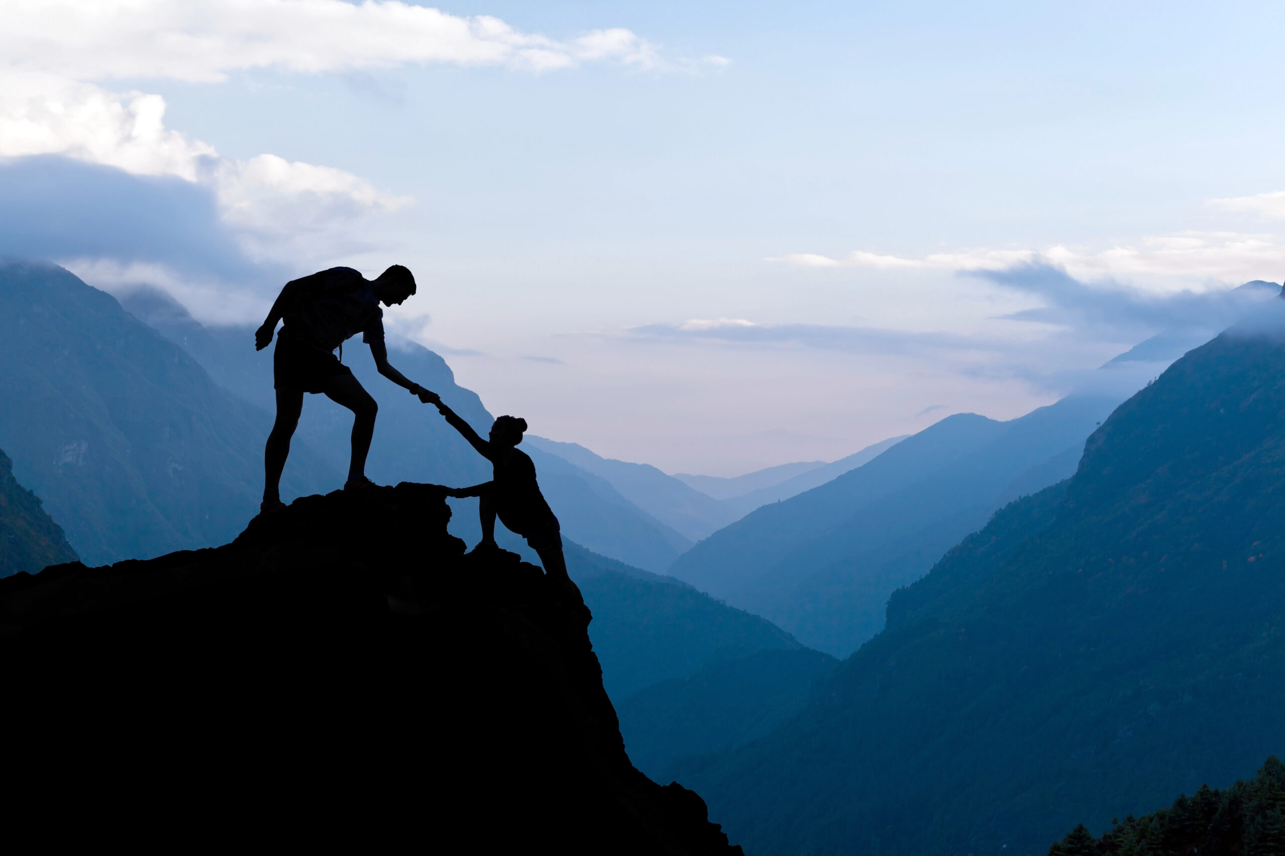 Two hikers helping each other on mountain.